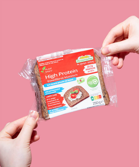 Brot in zwei Händen vor rosa Hintergrund