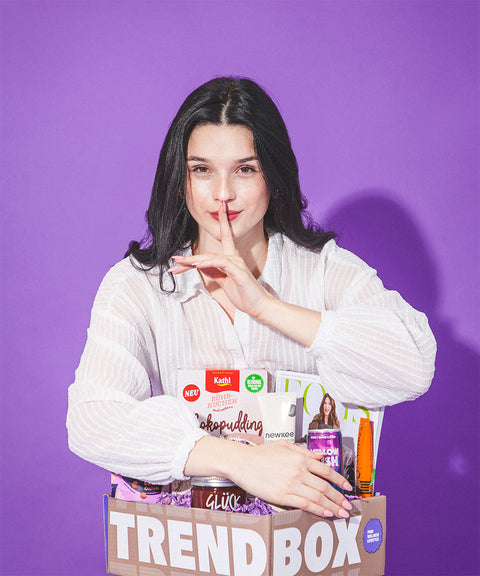 Frau verdeckt Box und hält Finger vor den Mund