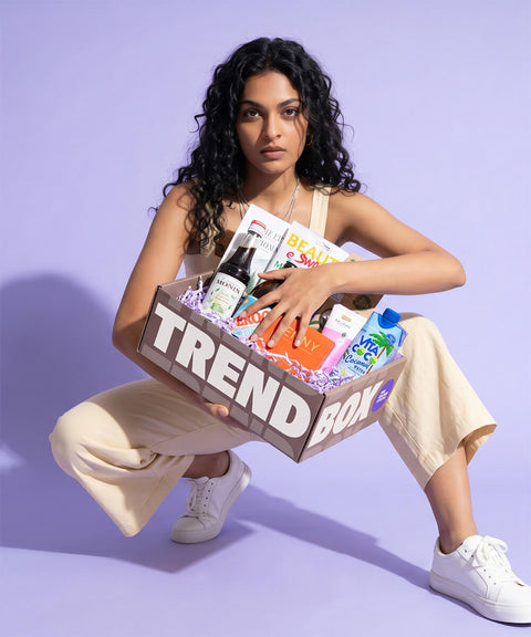 Frau mit Trendbox Juni in der Hand auf Flieder farbigen Hintergrund