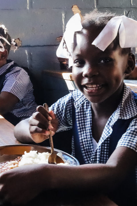 Kind in der Schule mit Essen auf dem Tisch