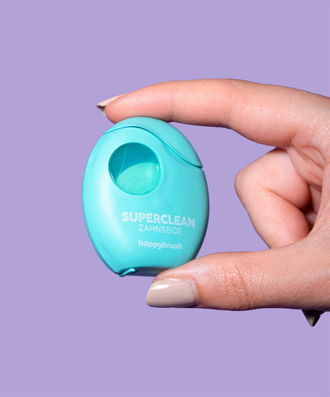 Hand hält Zahnseidepackung auf lila hintergrund