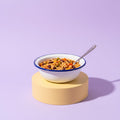 Schale mit Schulmahlzeit aus Reis, Bohnen und Gemüse auf gelbem Sockel